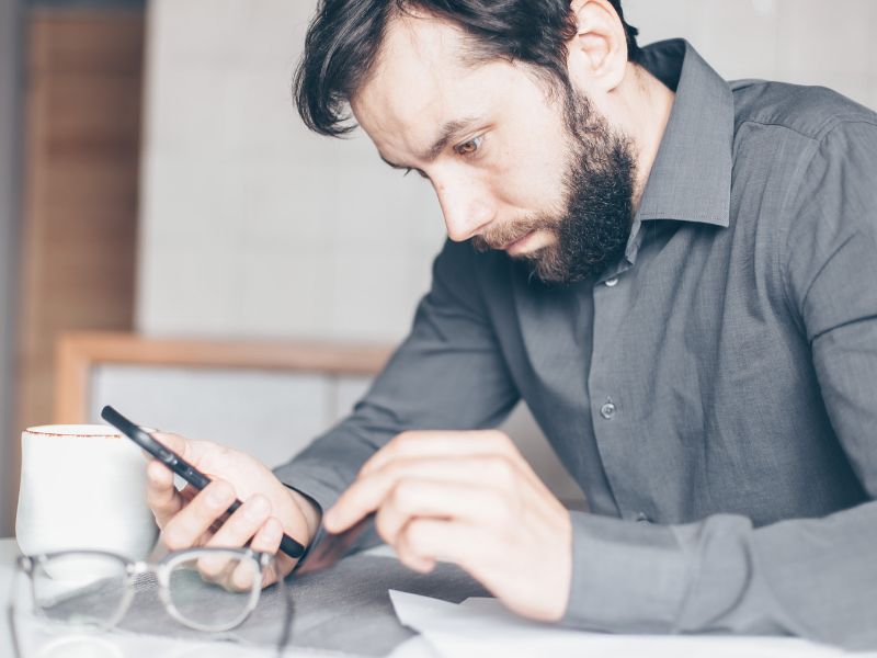 uomo con smartphone tiene la testa bassa