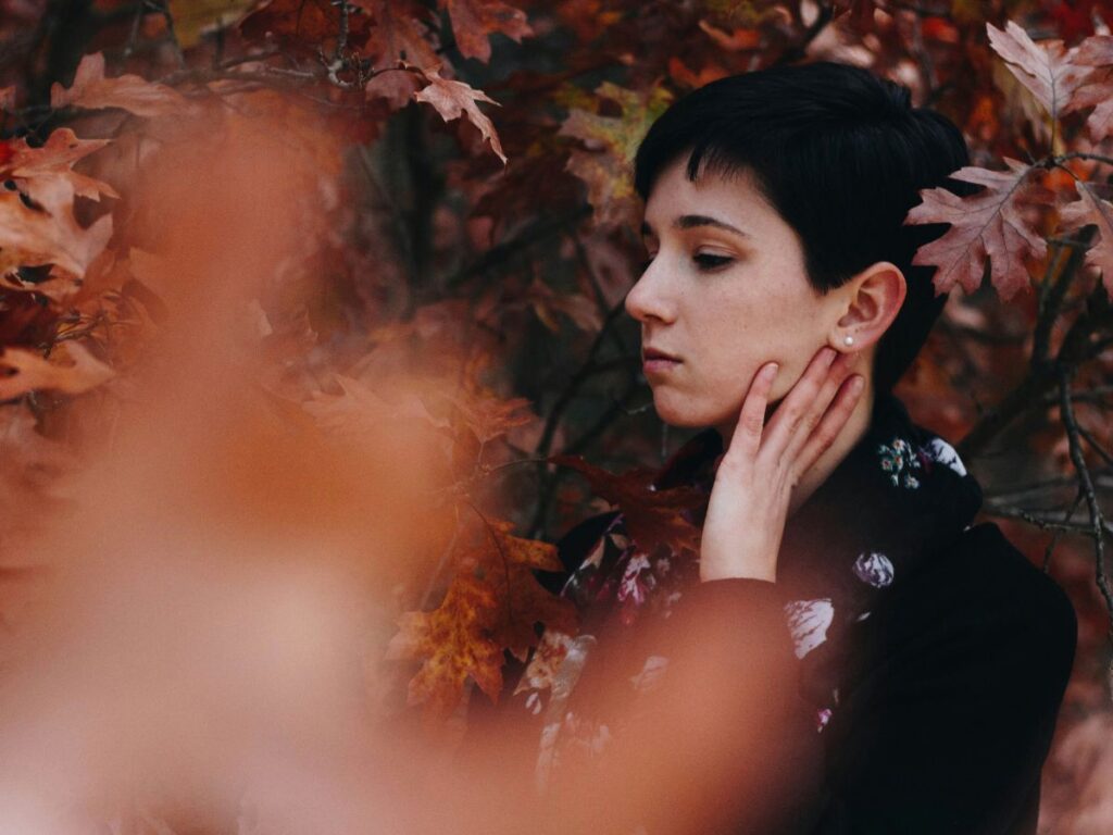 donna in paesaggio autunnale si tocca la pelle del viso