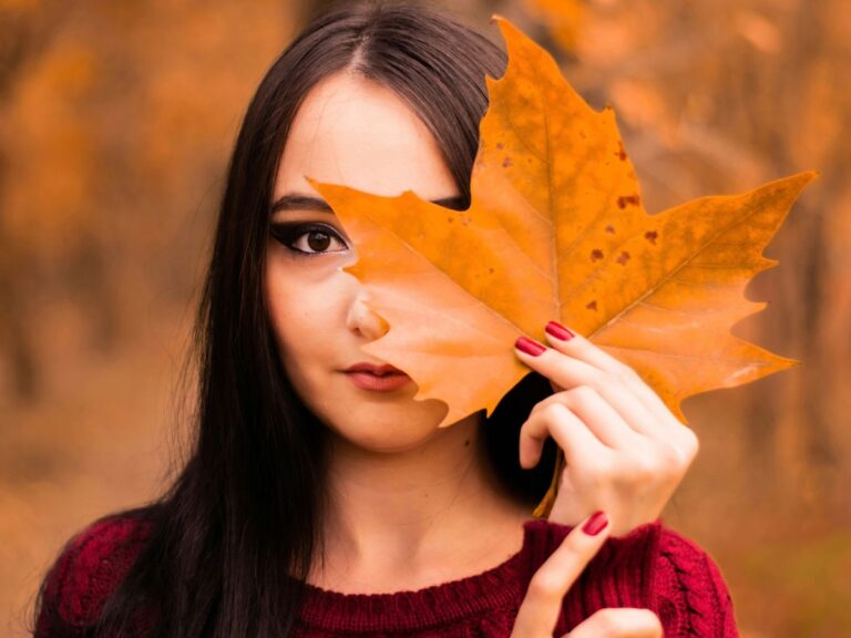 donna con foglia autunnale si copre il volto