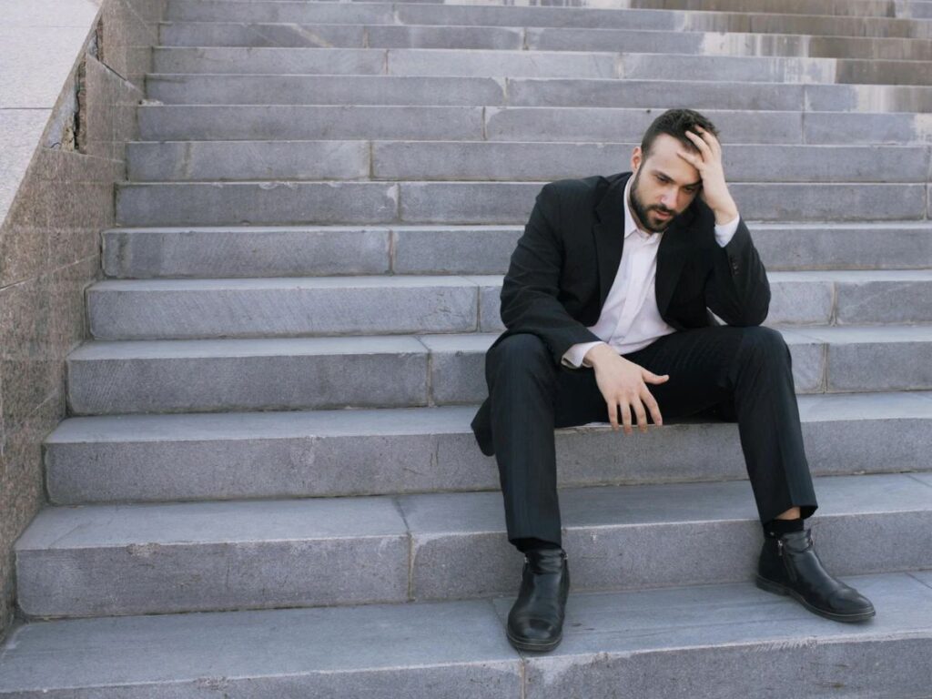 uomo seduto su scalini stressato