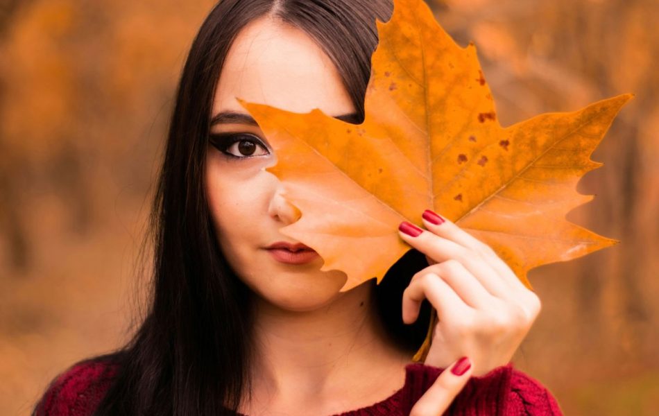 donna con foglia autunnale si copre il volto